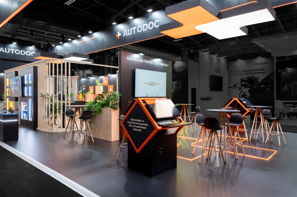 Photo de côté du stand sur-mesure réalisé par R2 Stand pour Autodoc sur le salon Equipauto avec la reprise du logo au sol par des leds aux couleurs de la marque
