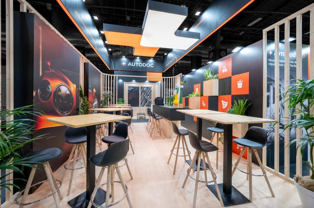 Vue d'intérieur du stand sur-mesure réalisé par R2 Stand pour Autodoc sur le salon Equipauto mettant en avant l'espace bar et l'enseigne customisée pour la marque