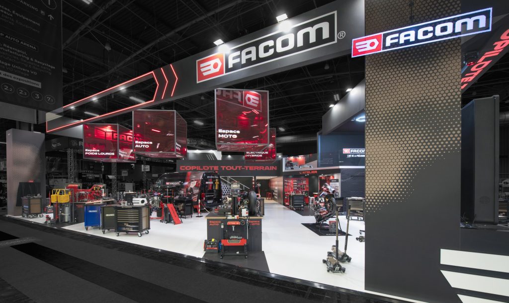 Photo d'ensemble du stand sur-mesure Facom réalisé par R2 Stand sur le salon Equipauto avec l'hologramme Facom qui habille le poteau technique du stand