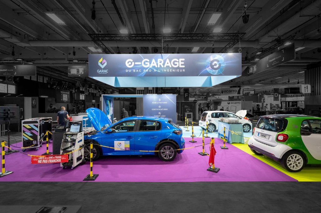 Vue de face du stand modulaire créé par R2 Stand pour son client Garac lors du salon Equipauto avec les différentes voiture servant à présenter les services proposés