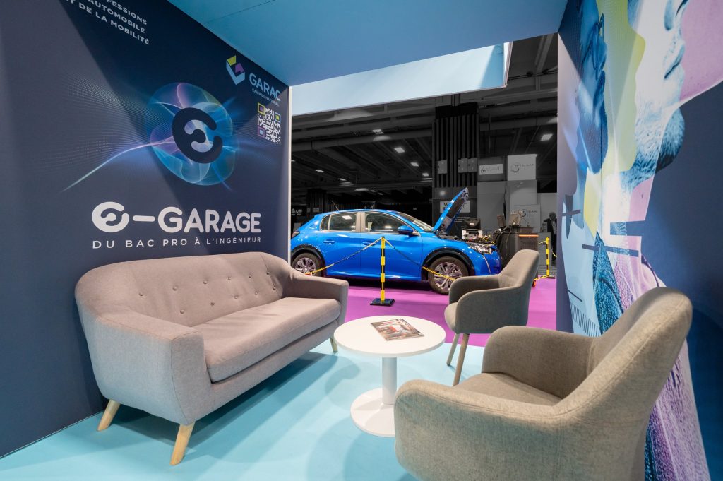 Vue de l'espace salon du stand modulaire créé par R2 Stand pour son client Garac lors du salon Equipauto avec une voiture du stand en second plan