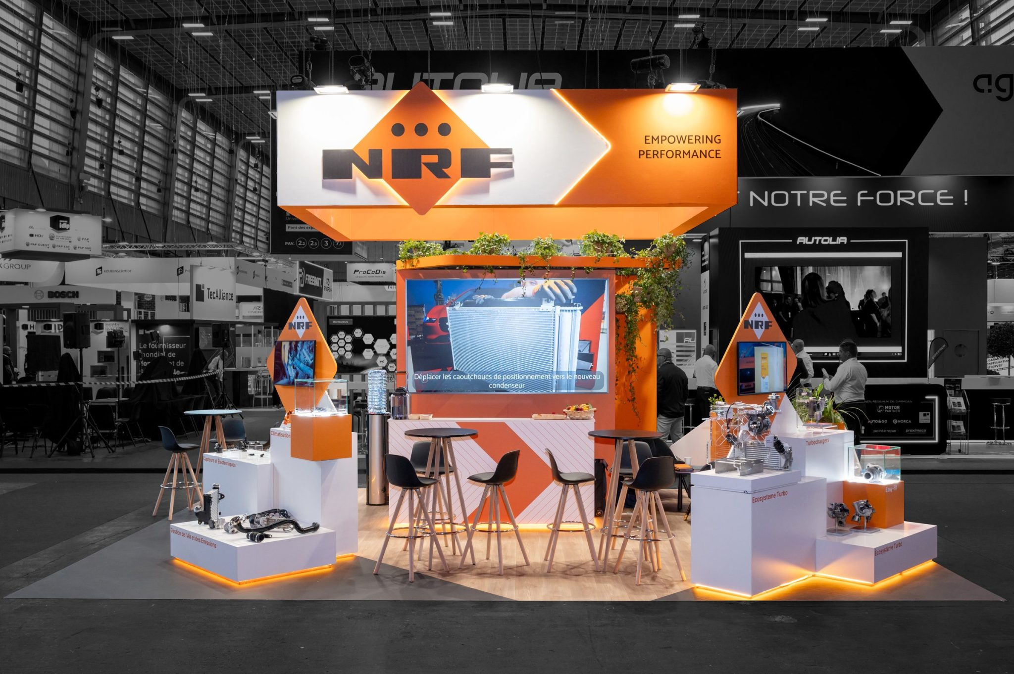 Front view of the custom-made stand in the Dutch brand's colors, created by R2 Stand for NRF at the Equipauto trade show, featuring a product podium, bar, and giant screen.