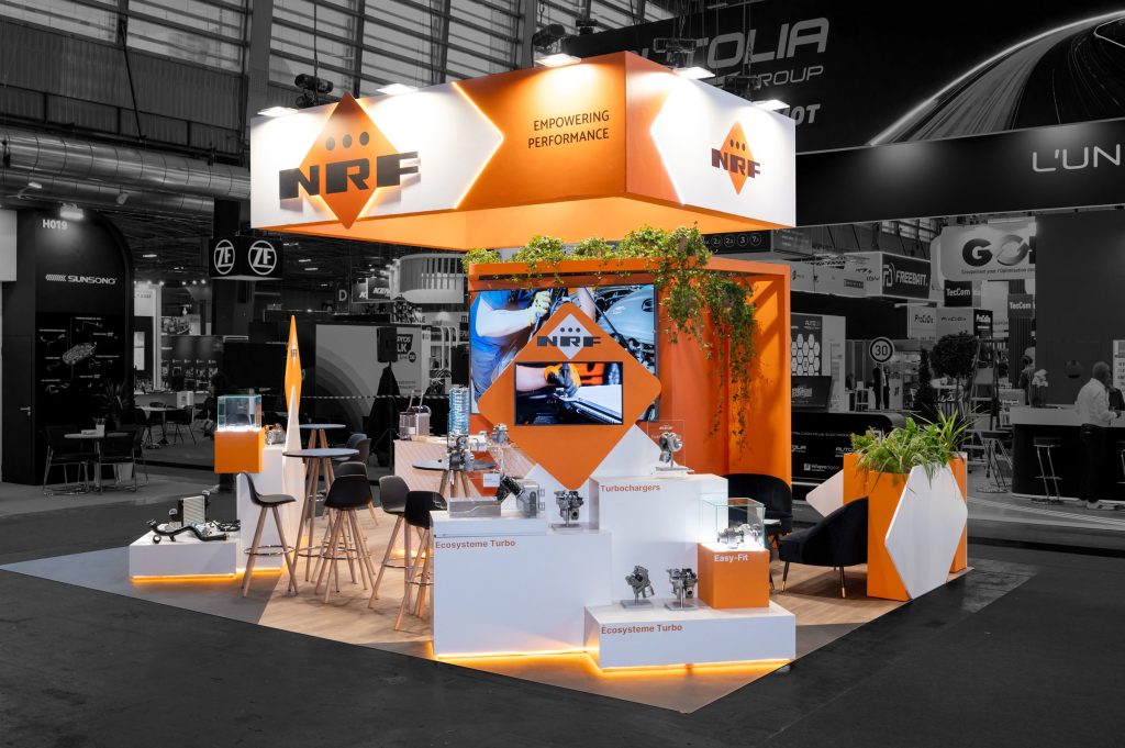 Photo d'angle du stand sur-mesure aux couleurs de la marque hollandaise réalisé par R2 Stand pour NRF sur le salon Equipauto avec podium produits et espace receptif