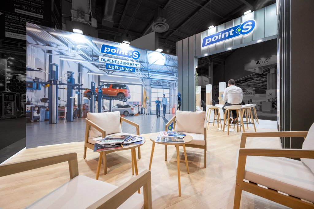 Photo du coin salon du stand sur-mesure réalisé par l'agence R2 Stand Lyon pour son client Point S ainsi que son espace réceptif en second plan