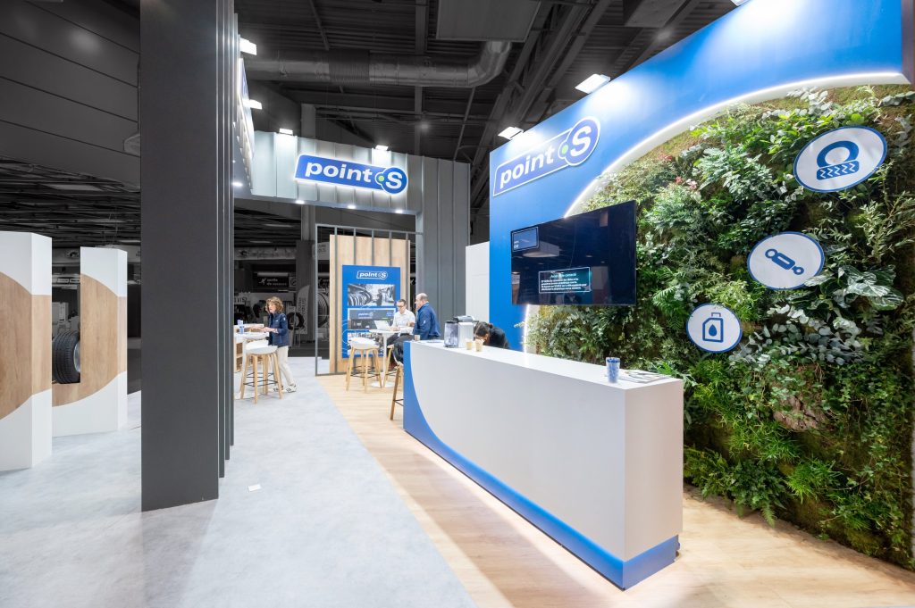 Photo du comptoir d'accueil du stand sur-mesure réalisé par l'agence R2 Stand Lyon pour son client Point S ainsi que son espace réceptif en second plan