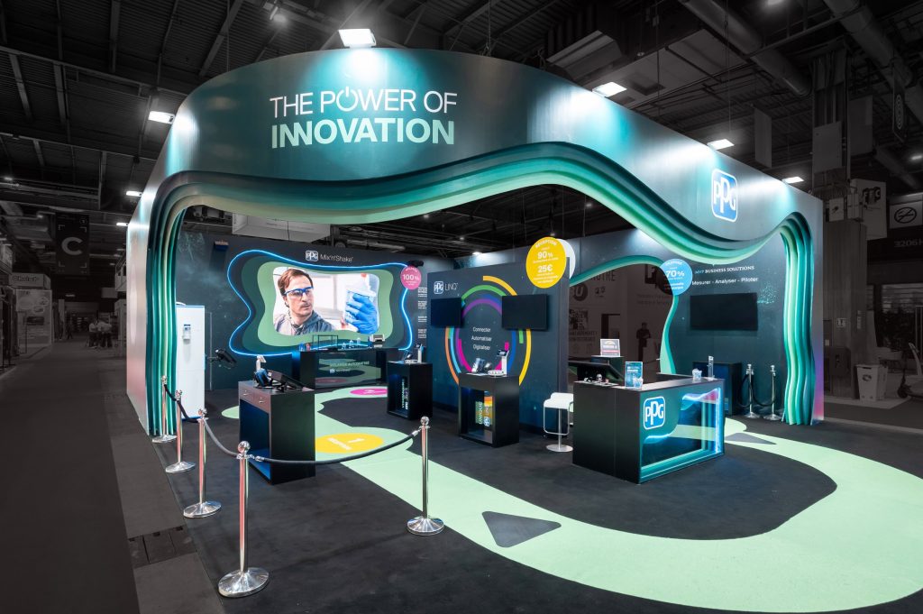 Angled view of the visitor area of the custom-built stand created by R2 Stand and Event for its client PPG at the Equipauto trade show, highlighting the colorful and vibrant design of the stand as well as the various elements used to present the solutions on offer.