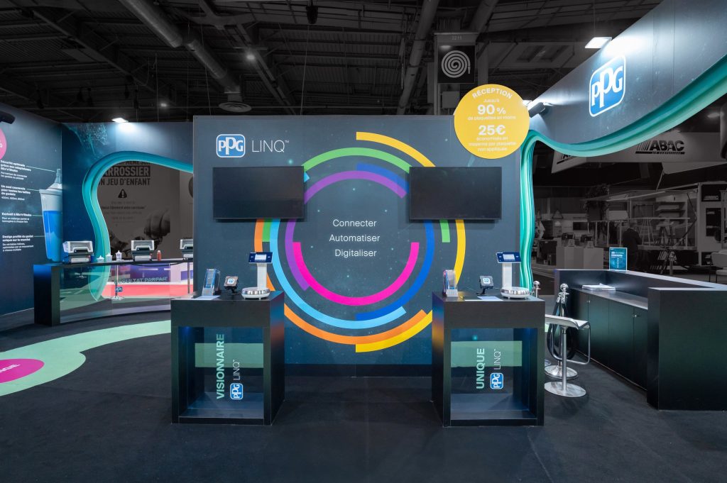 Vue d'une partie de l'intérieur du stand réalisé par R2 Stand et Event pour son client PPG sur le salon Equipauto montrant des comptoirs de démonstration produits