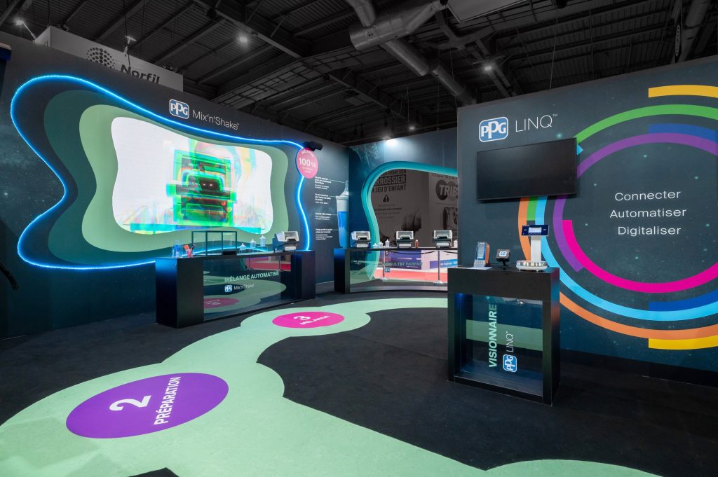 Photo de l'intérieur du stand sur-mesure réalisé par R2 Stand et Event pour son client PPG sur le salon Equipauto mettant en avant le parcours visiteurs rythmé par les différentes étapes du nouveau concept de la marque avec son marquage au sol et les comptoirs sur-mesure