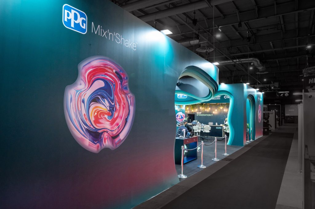 Photo de côté du stand sur-mesure réalisé par R2 Stand et Event pour son client PPG sur le salon équipauto mettant en avant les arches originales très originales contrastant avec une moquette noire