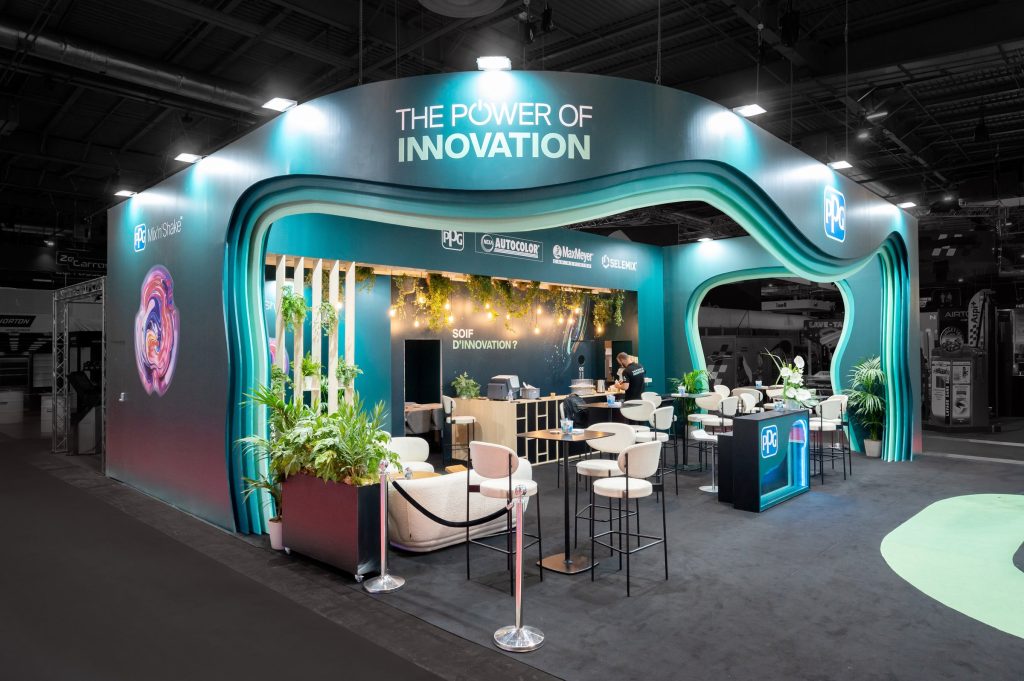 Photo de la partie réceptive du stand sur-mesure réalisé par R2 Stand et Event pour son client PPG sur le salon équipauto mettant en avant les arches colorées très originales contrastant avec une moquette noire
