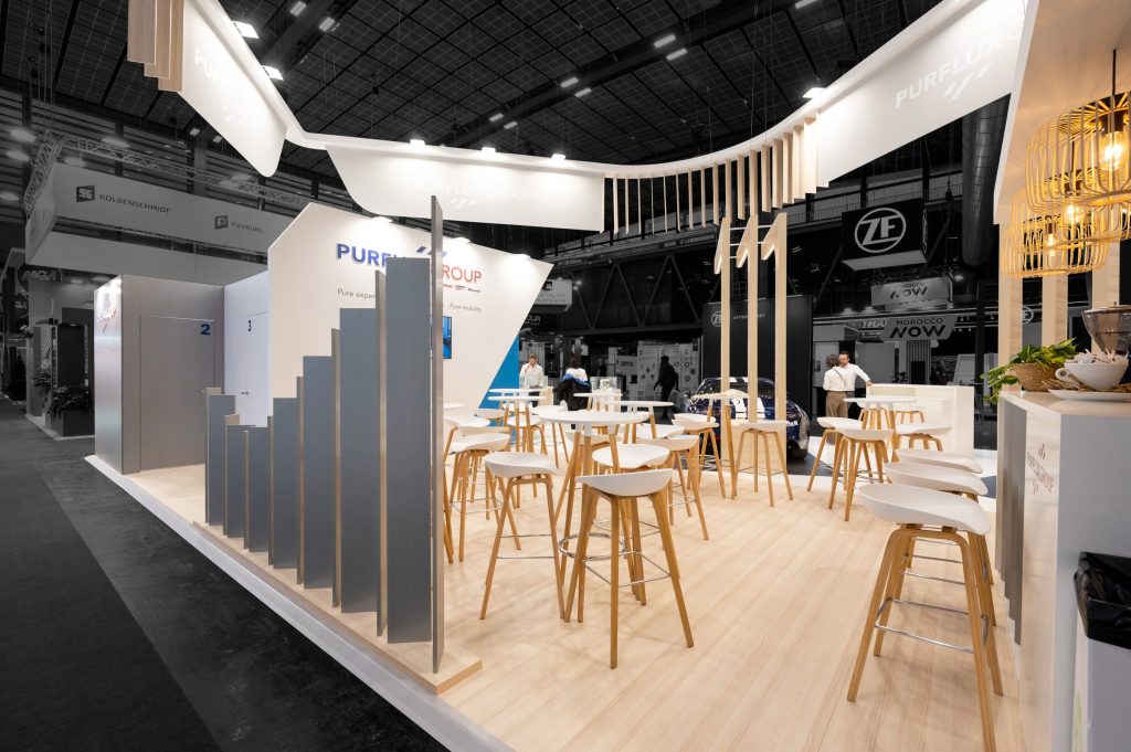 Photo de la zone de réception du stand sur mesure Purflux réalisé par R2 Stand sur Equipauto, mis en avant de la magnifique enseigne customisée et des claustras de séparation
