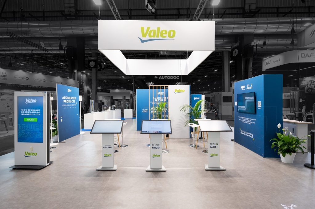Vue du stand modulaire créé par R2 Stand pour Valéo au salon Equipauto, vue latérale avec écran de loterie et terminaux à écran tactile.