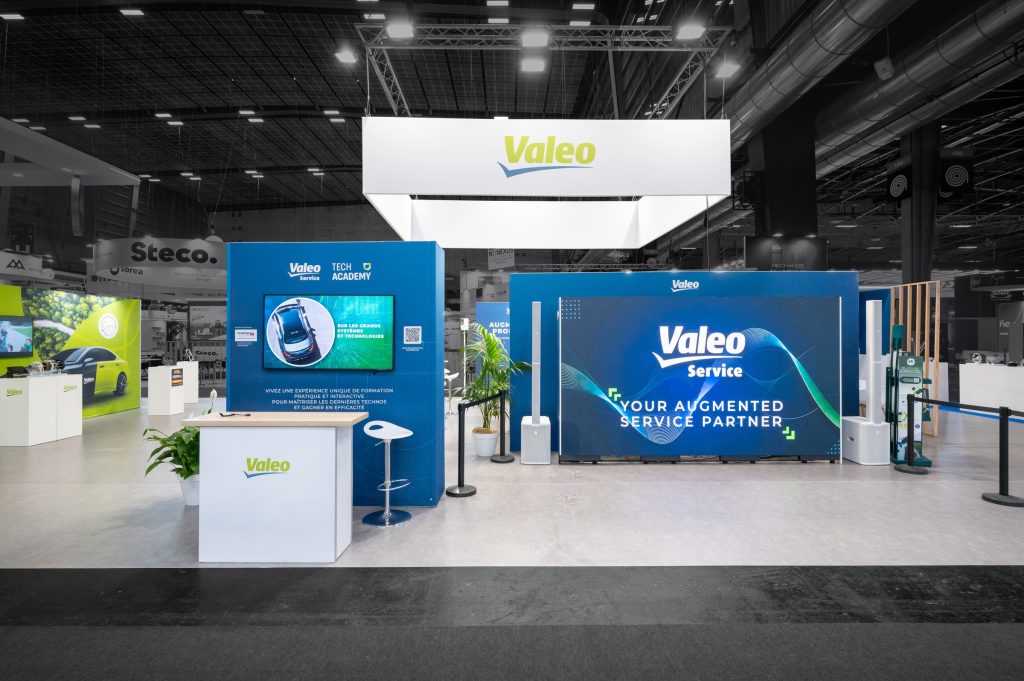 Photo de côté du stand modulaire Valeo réalisé par R2 Stand sur Equipauto, avec l'écran géant de l'espace conférence et le comptoir d'acceuil