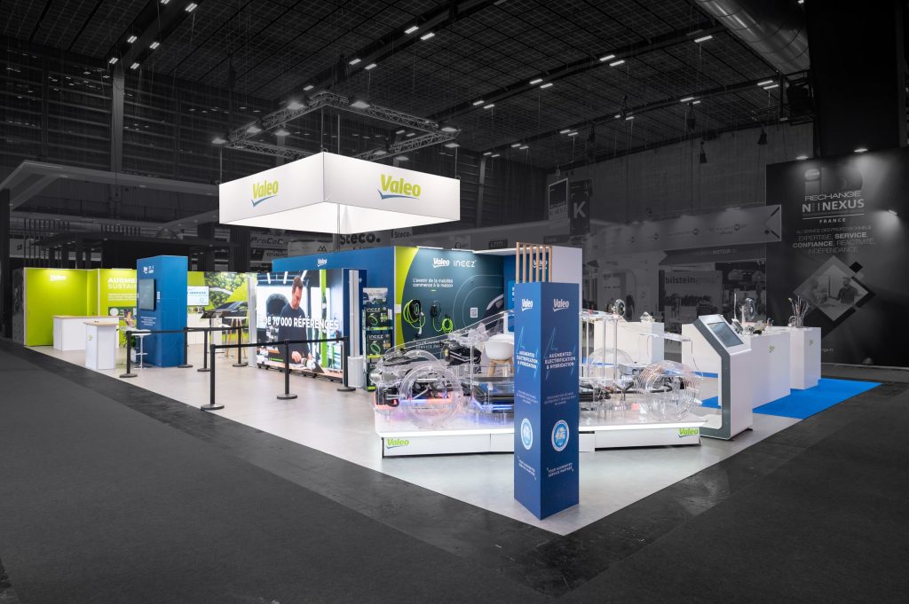 Photo de l'angle d'attaque du stand modulaire Valeo réalisé par R2 Stand sur Equipauto, avec vue sur la voiture de présentation des produits et l'écran géant
